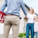 cropped shot of realtor with sold sign shaking hand of young wom cropped shot of realtor with sold sign shaking hand of young woman with daughter in front of new house