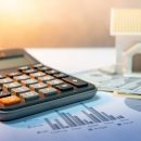 Real estate or property development. Construction business inves Real estate or property development. Construction business investment concept. Home mortgage loan rate. House model on international banknotes with calculator on the table.